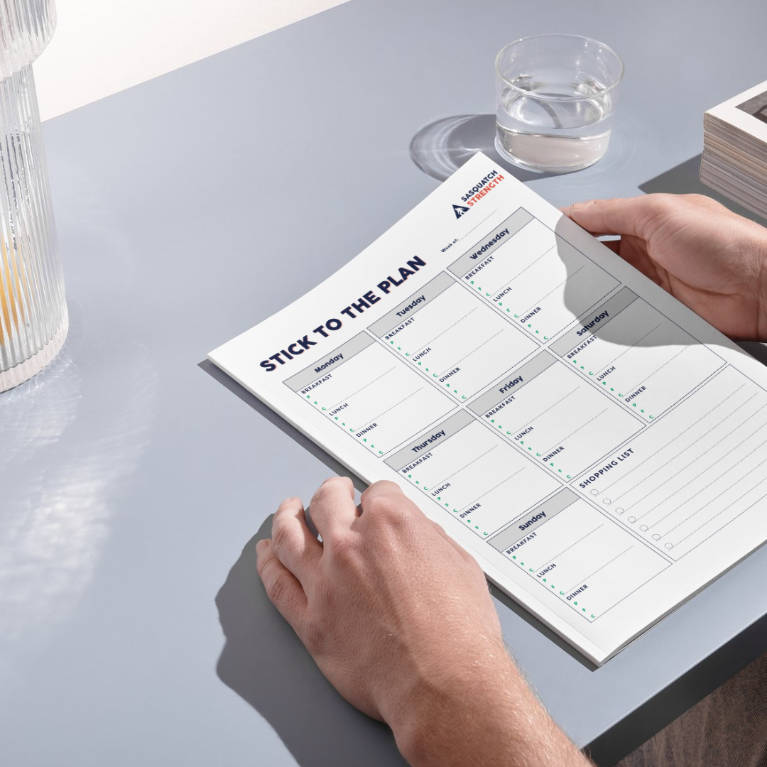 A person is holding a piece of paper that says stick to the plan