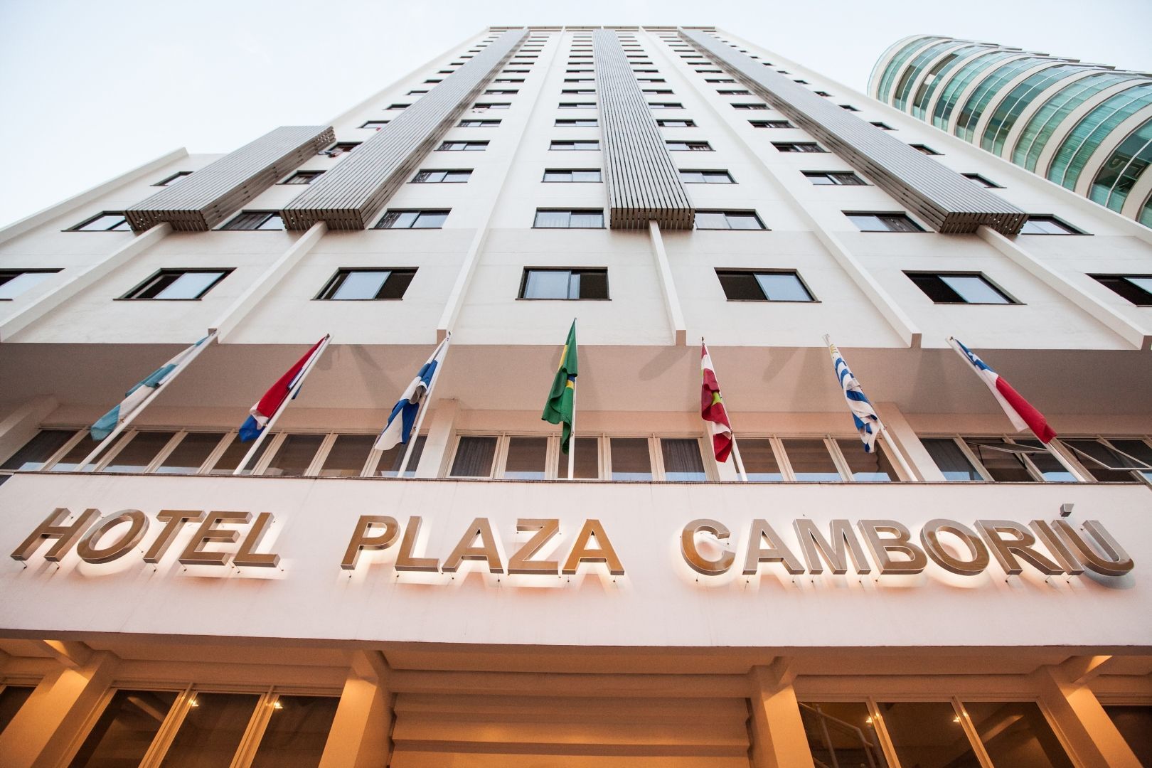 Hotel Plaza Camboriú, prédio branco com sinalização, bandeiras.