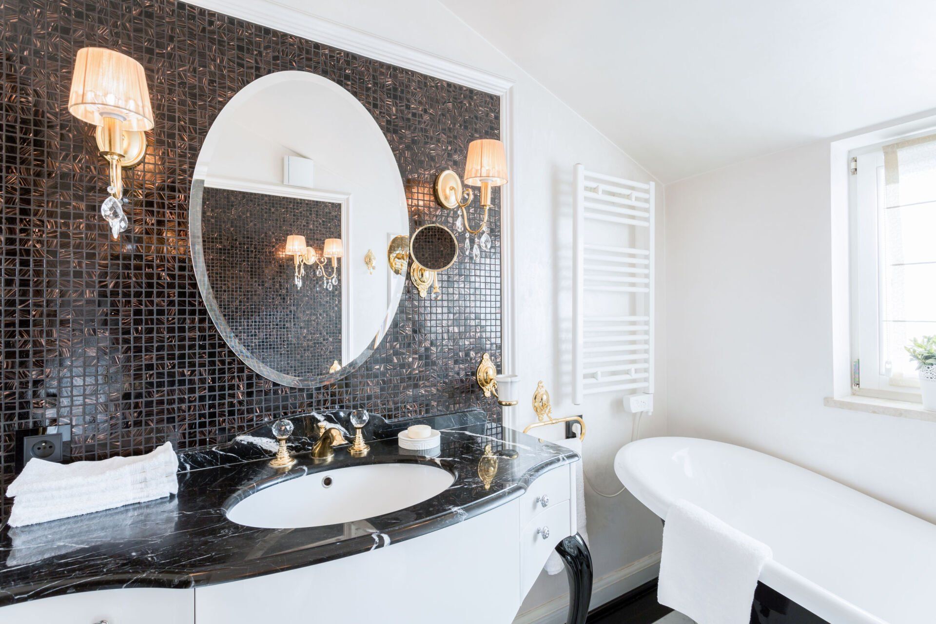 A bathroom with a tub , sink , mirror and window.