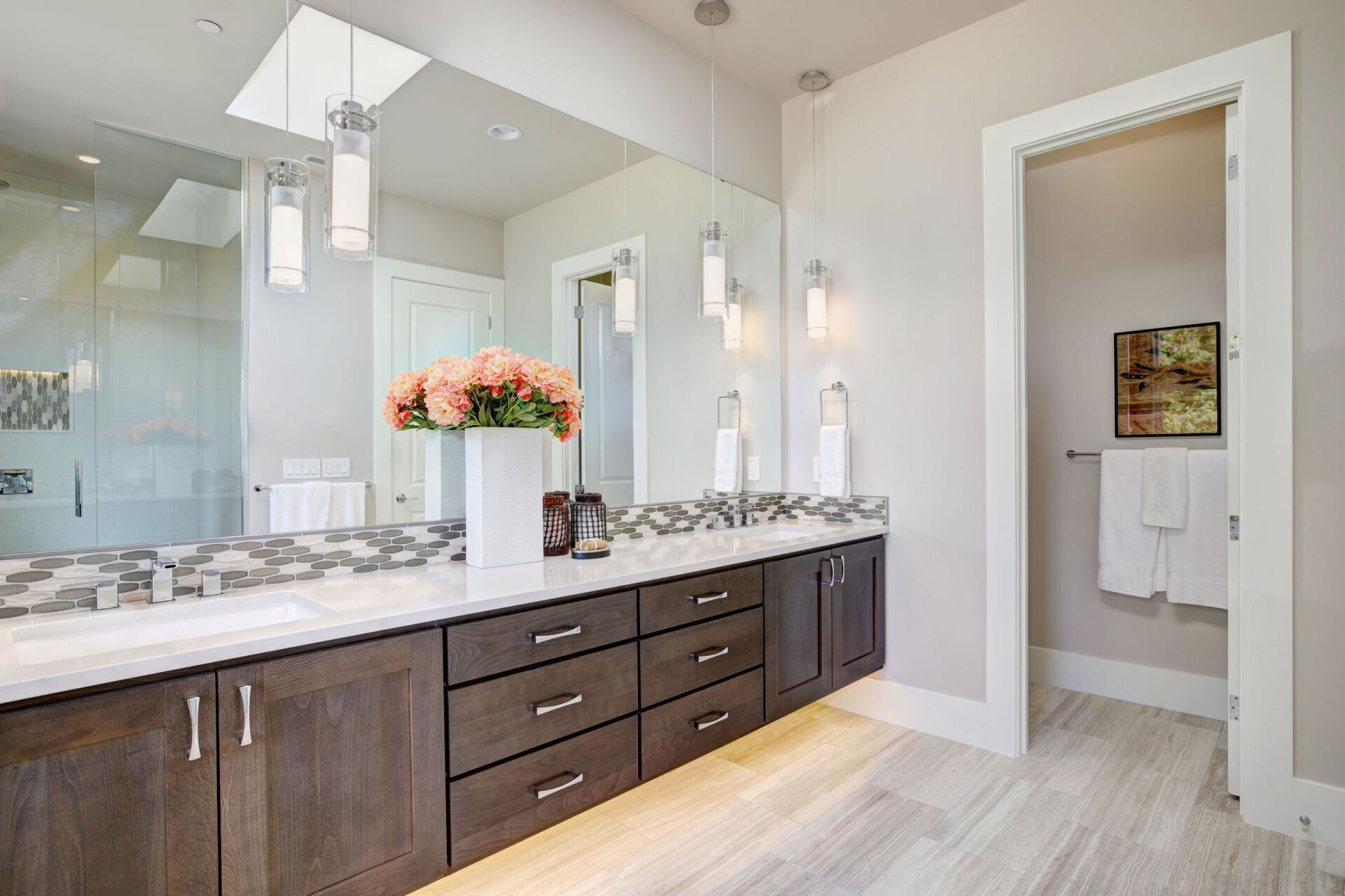 A bathroom with two sinks , a large mirror and a walk in shower.