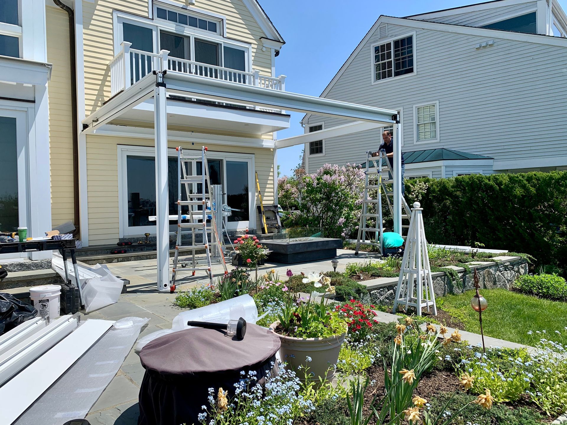 A man is standing on a ladder in the backyard of a house.