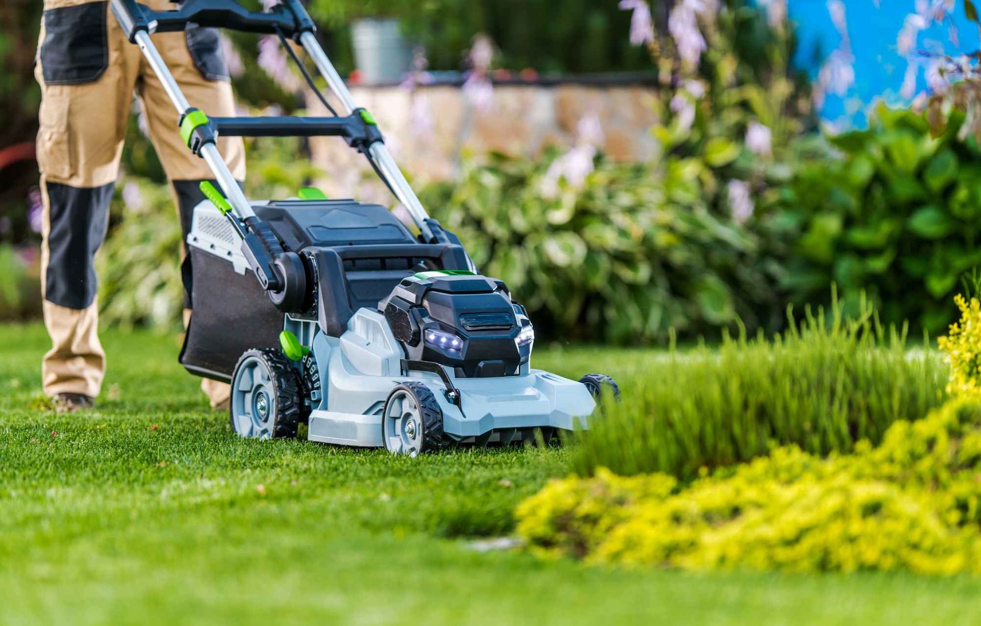 A man is mowing a lush green lawn with a  heavy duty lawn mower.