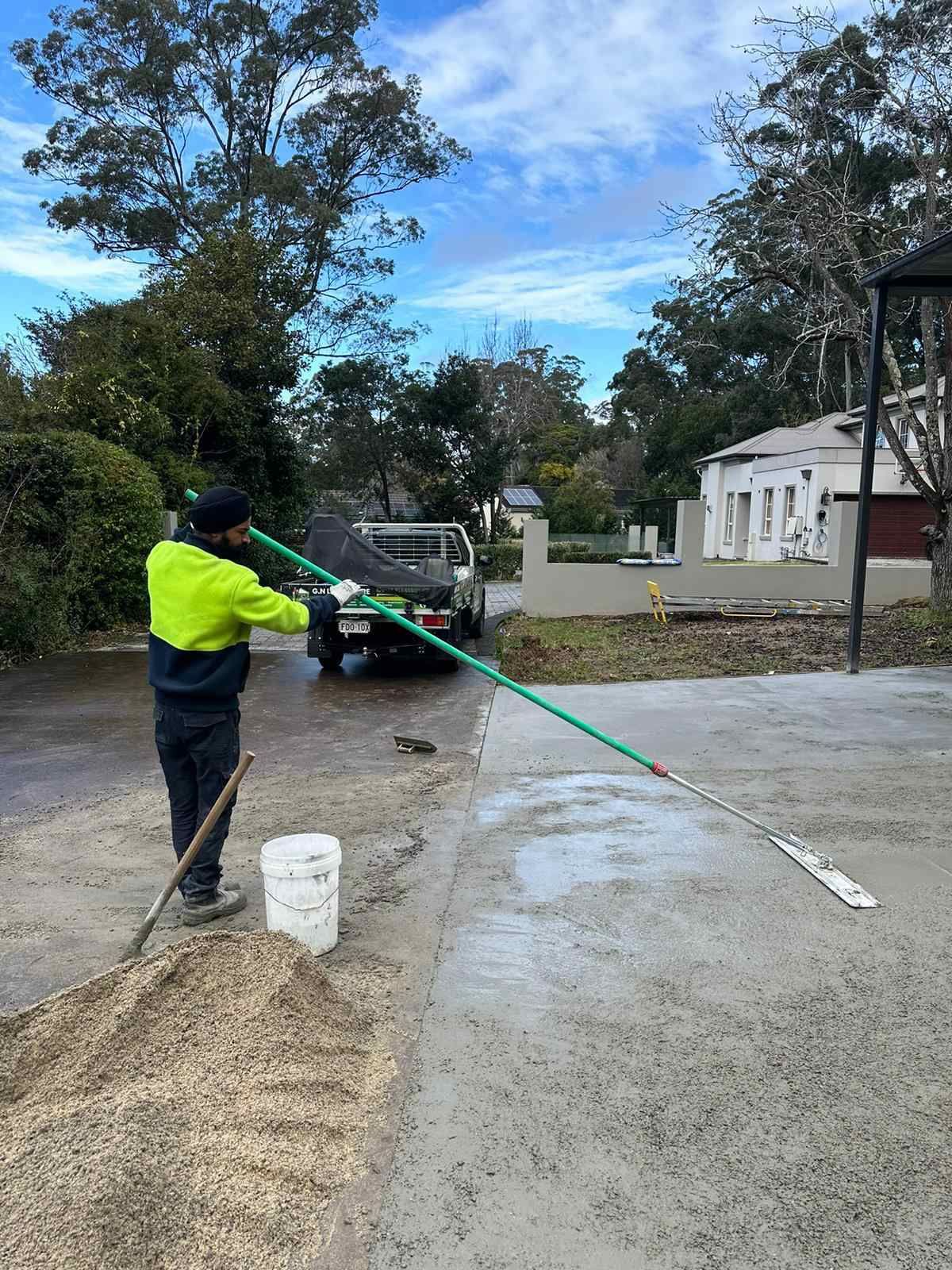 A man is cleaning a driveway with a mop.