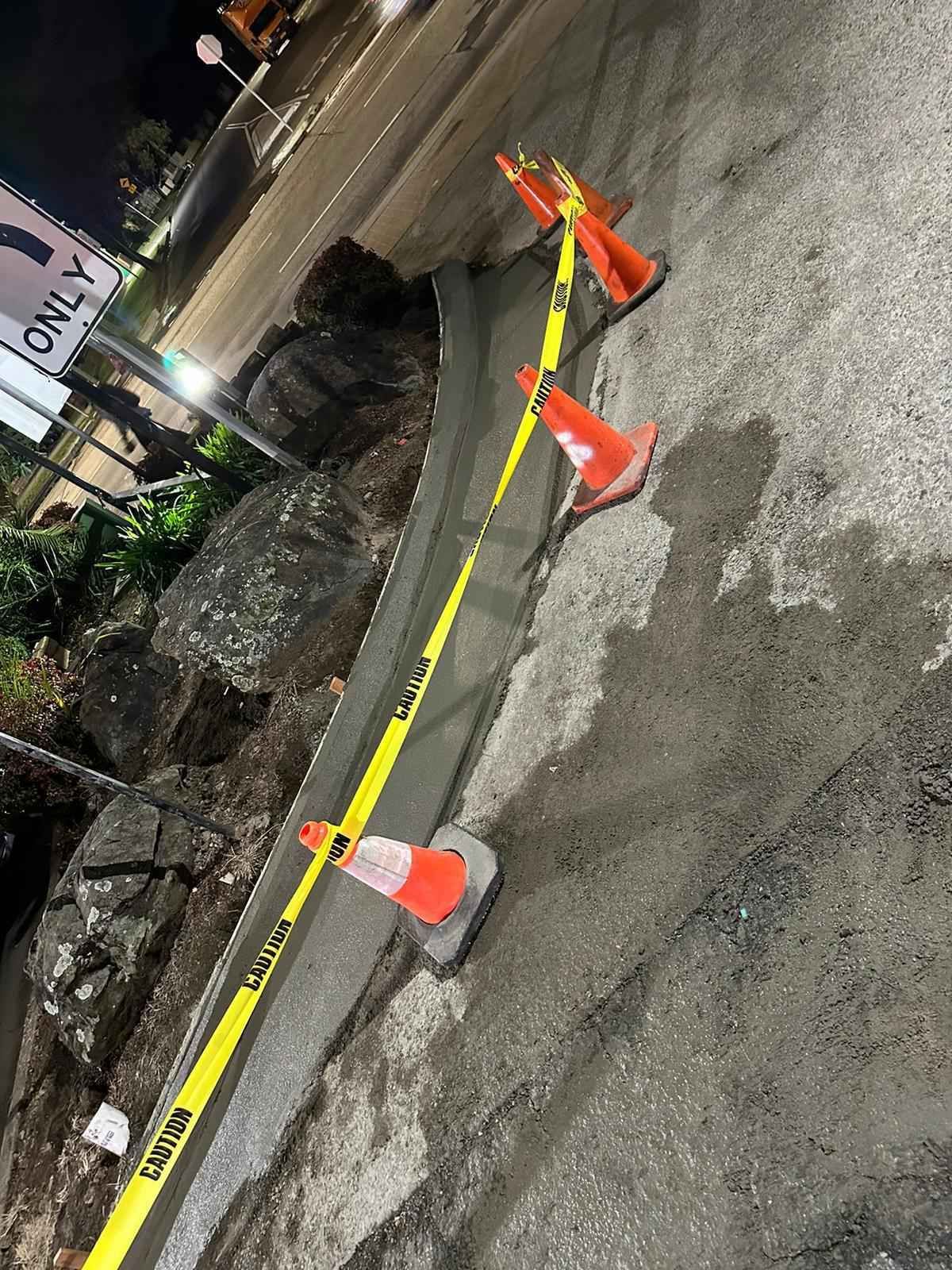 A bunch of traffic cones are sitting on the side of a road.