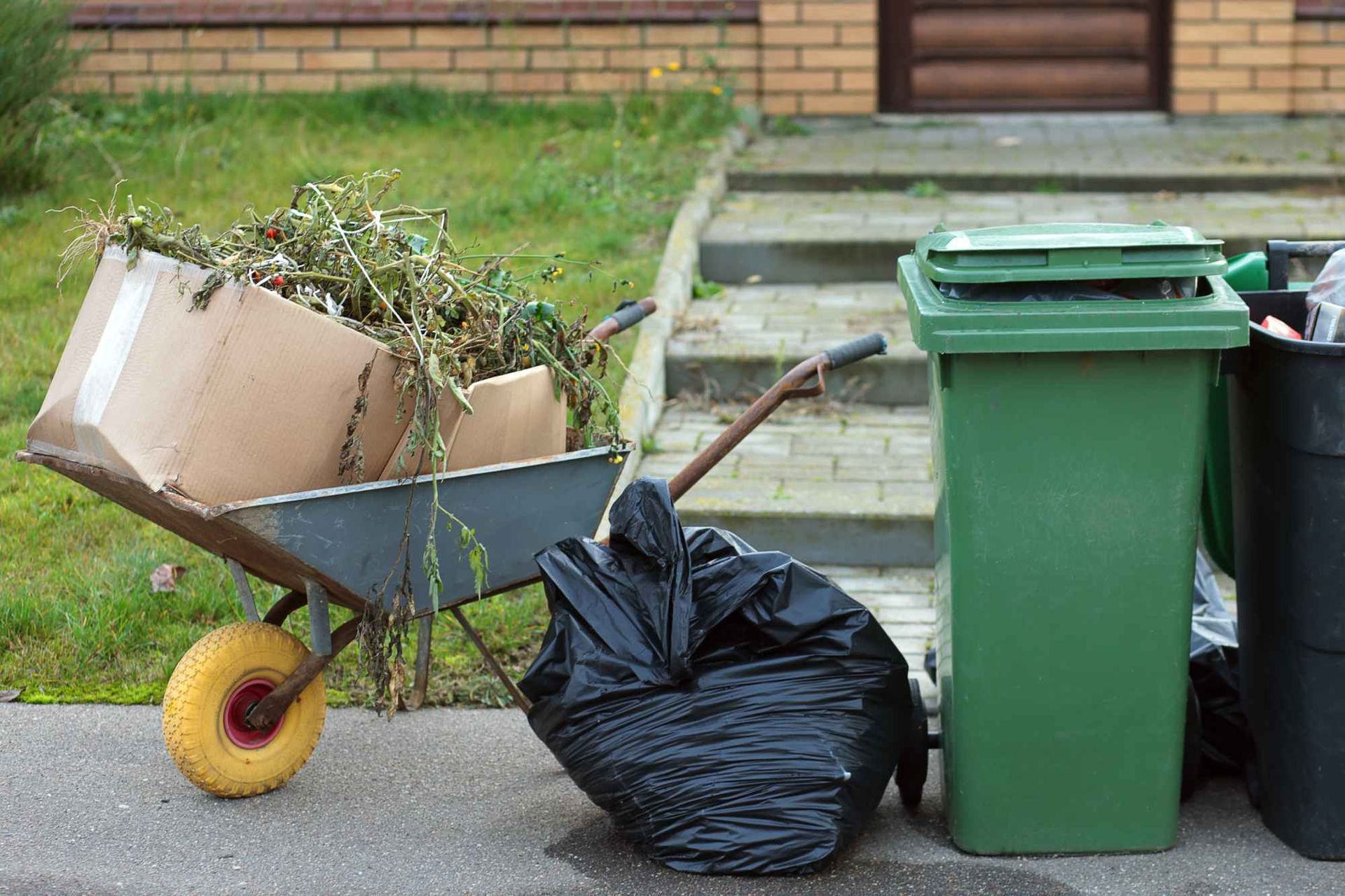 A wheelbarrow filled with cardboard boxes and trash bags.