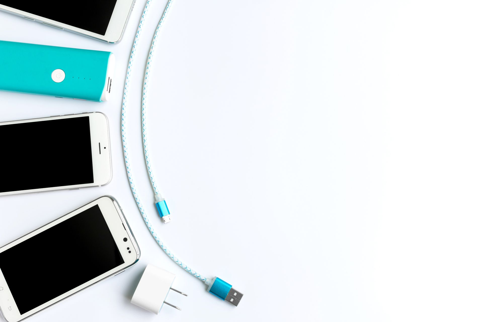 Tre telefoni, un power bank e un cavo di ricarica su una superficie bianca.