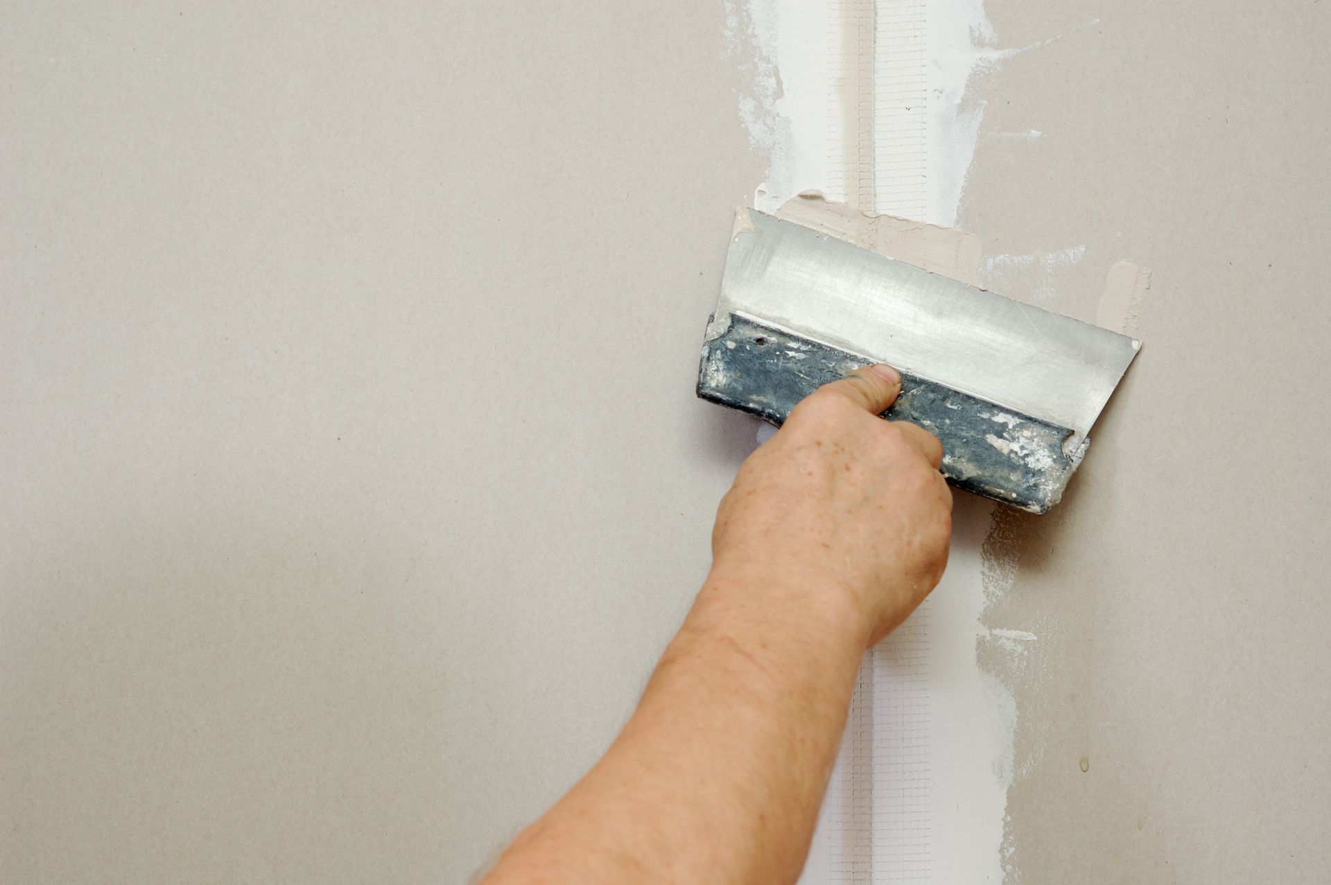 A person is plastering a wall with a spatula.