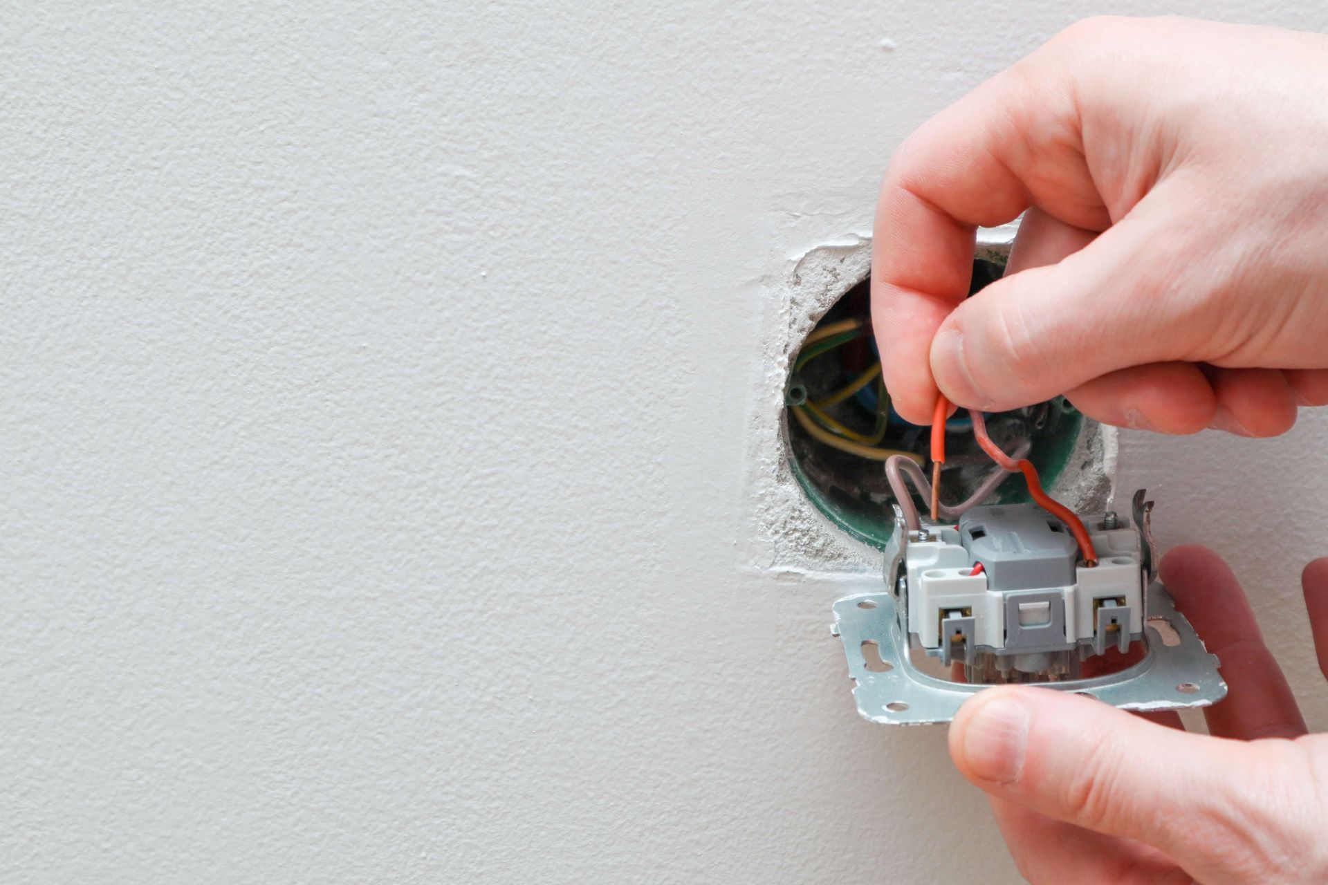 A person is installing a light switch on a wall.