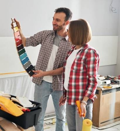 A man and a woman are looking at a palette of paint.