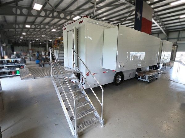 A white trailer with stairs leading up to it is parked in a garage.