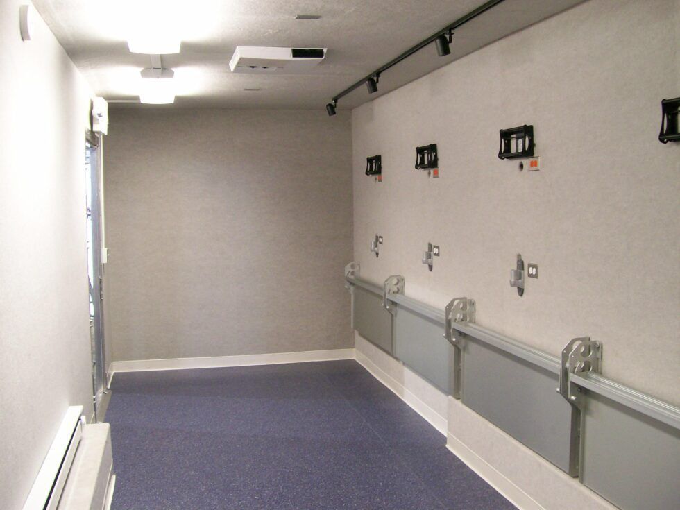 A long hallway with a purple carpet and a projector on the ceiling