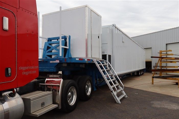 A red semi truck is parked next to a white trailer