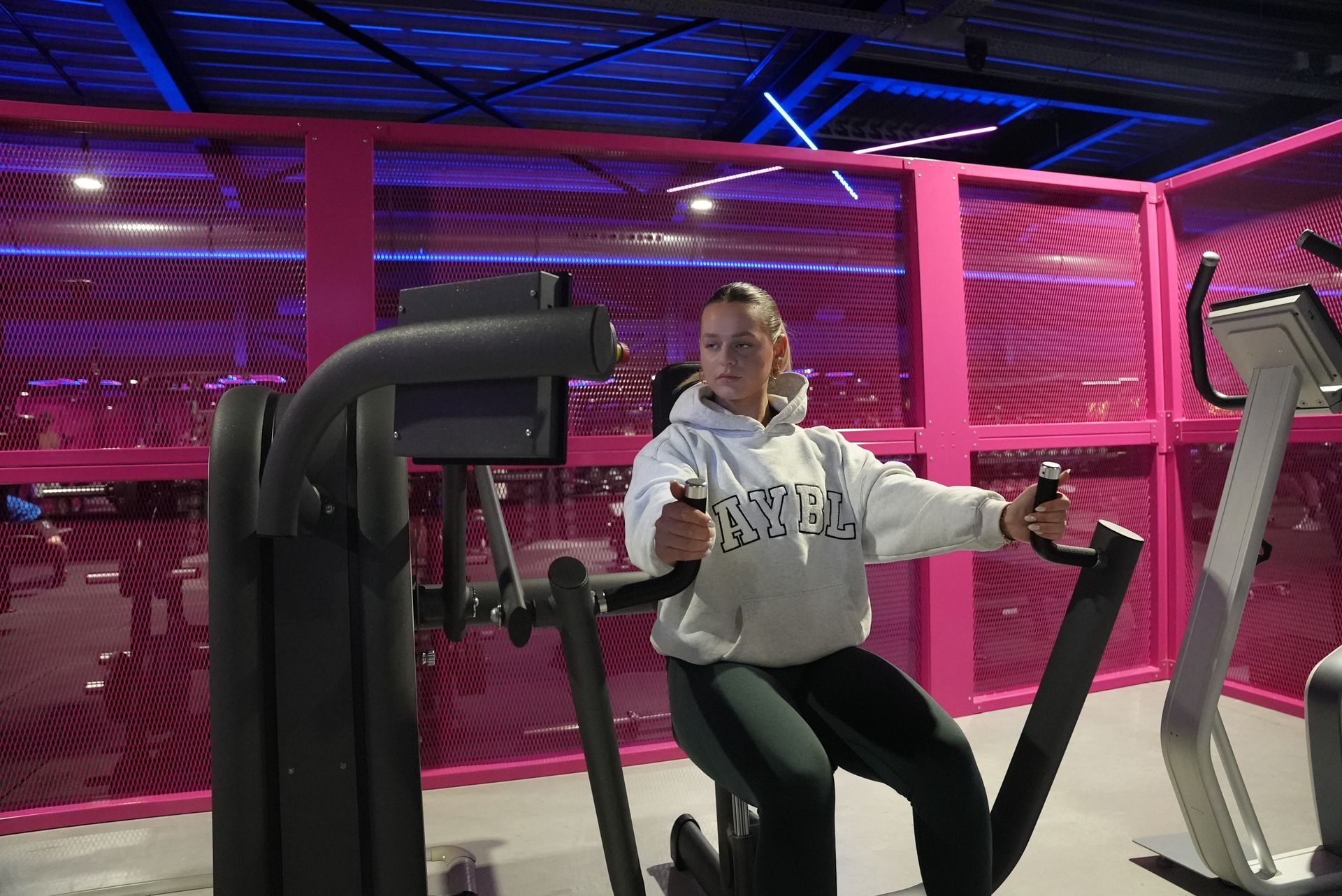 Een vrouw zit op een apparaat in een sportschool.