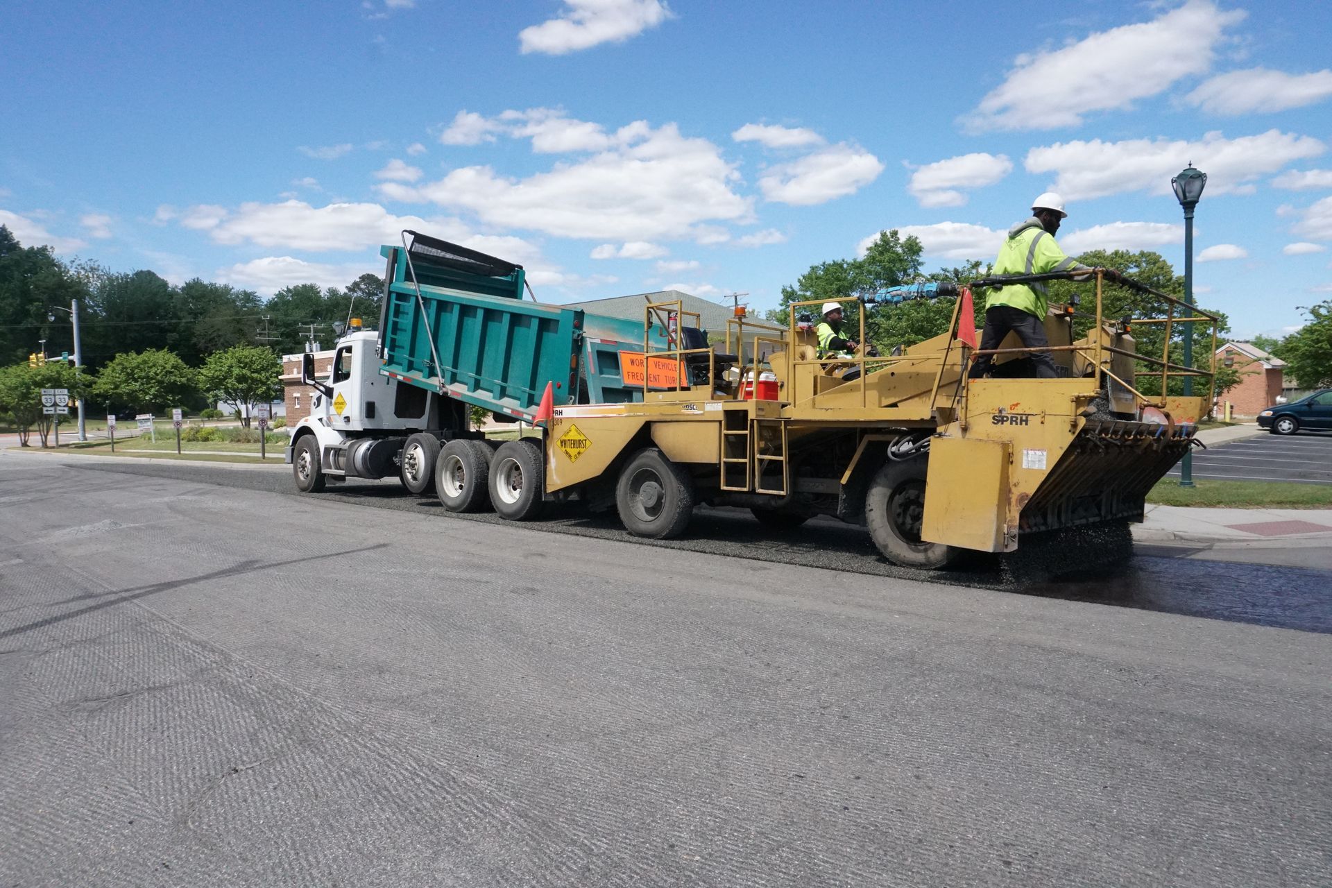 Dump truck feeding stone chips to the chip speader