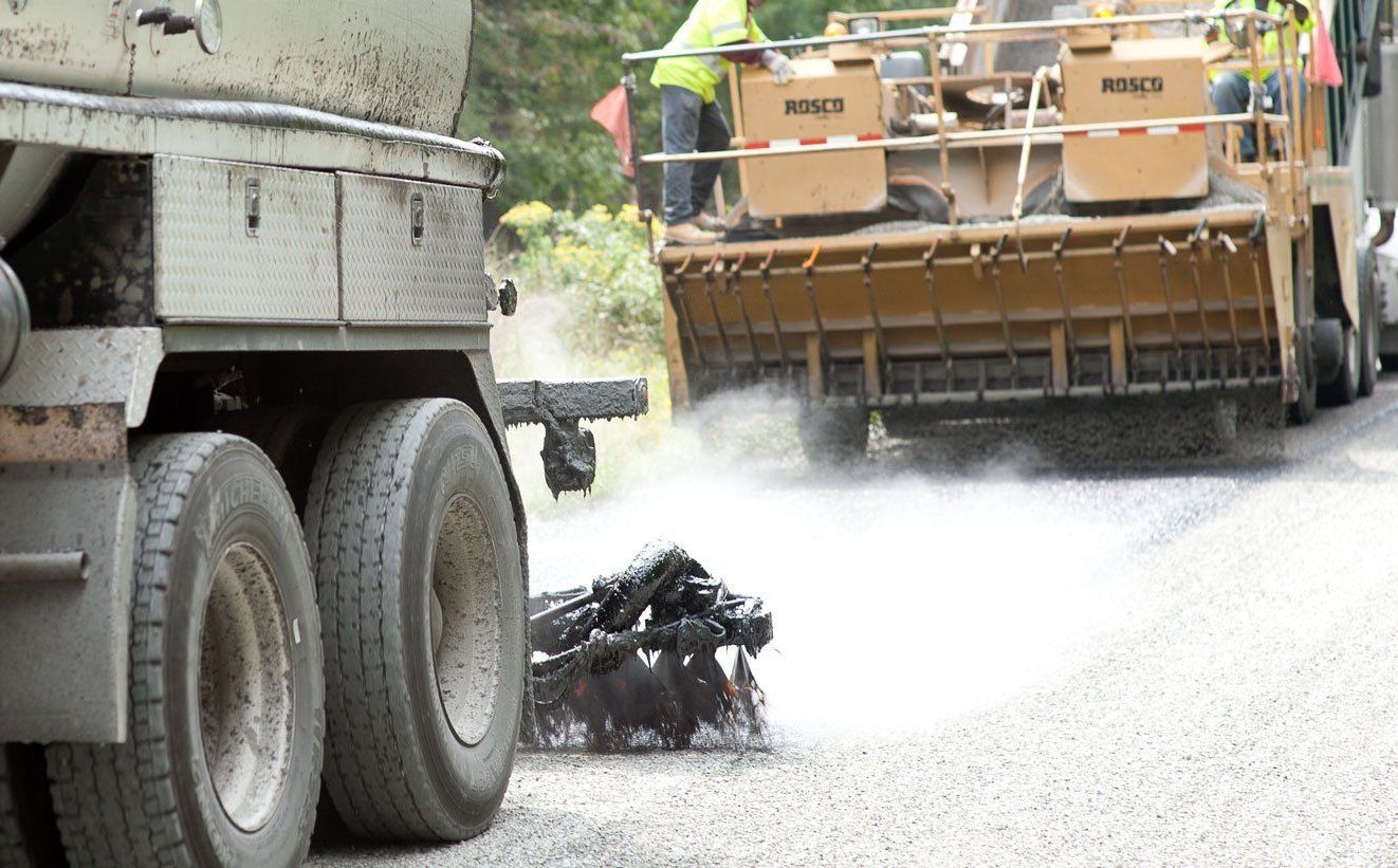 Emulsion spraying with chip spreader dropping chips.