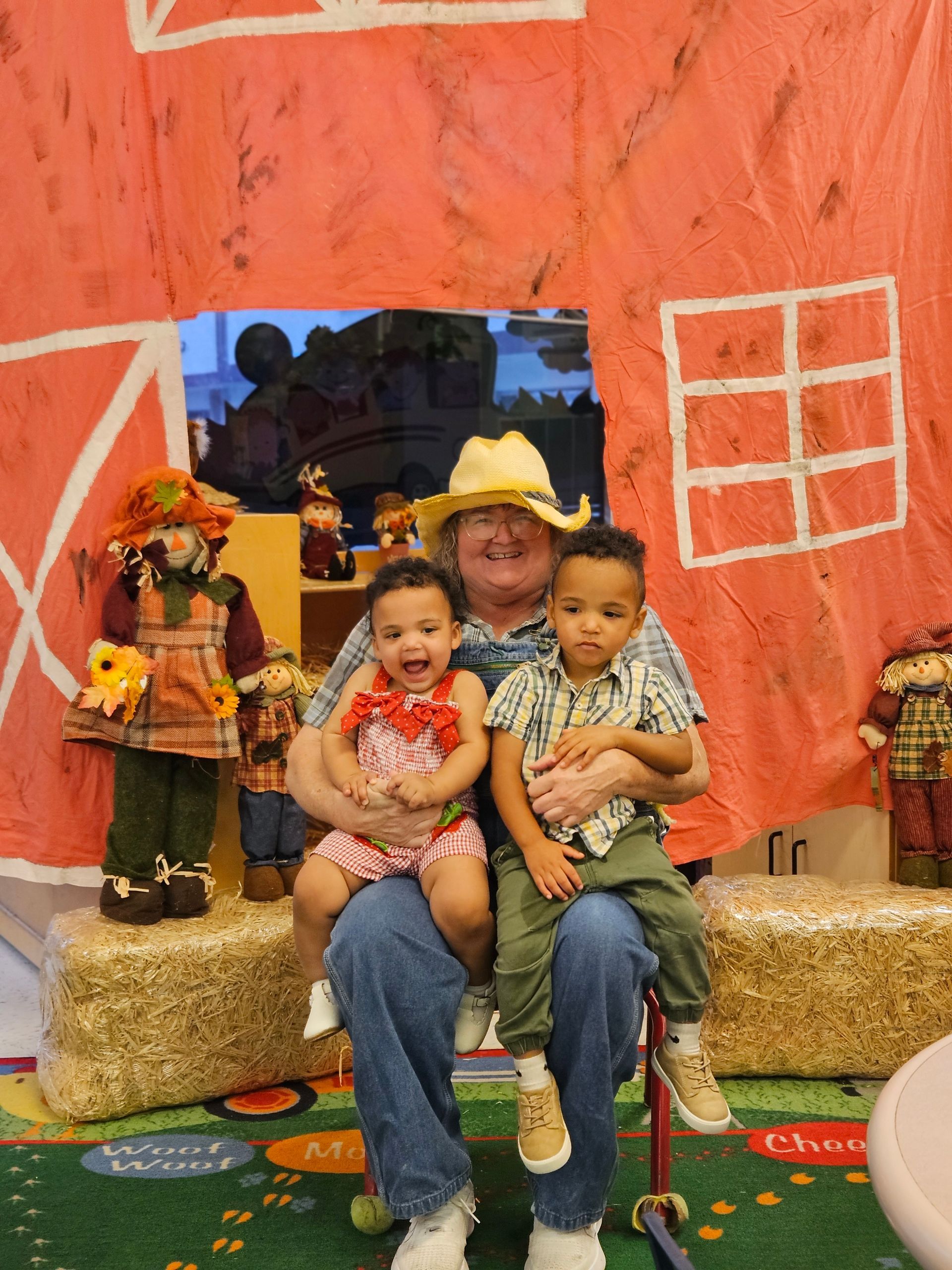 A group of children and two teachers smile in a bright classroom.