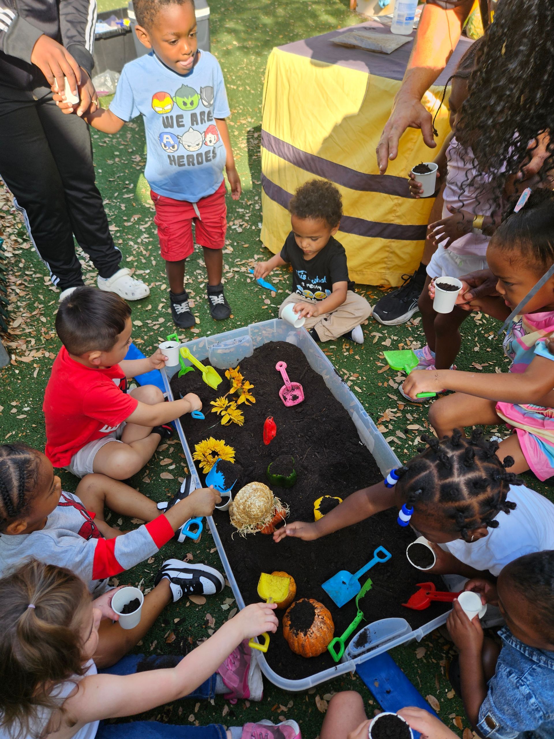 Children playing in a dirt pit with toys; bright colors, sunny day.