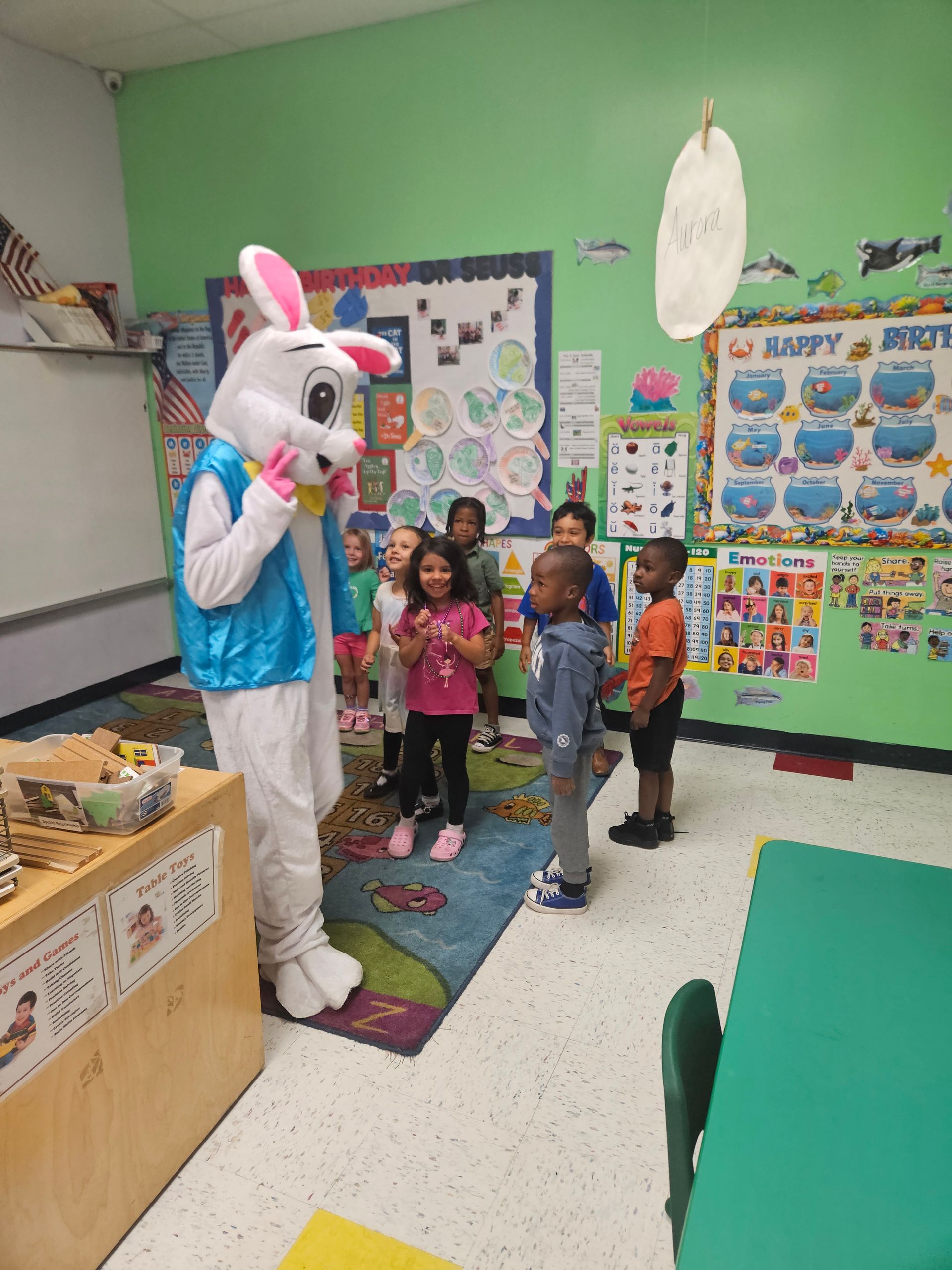 Easter Bunny with a group of children in a brightly colored classroom.