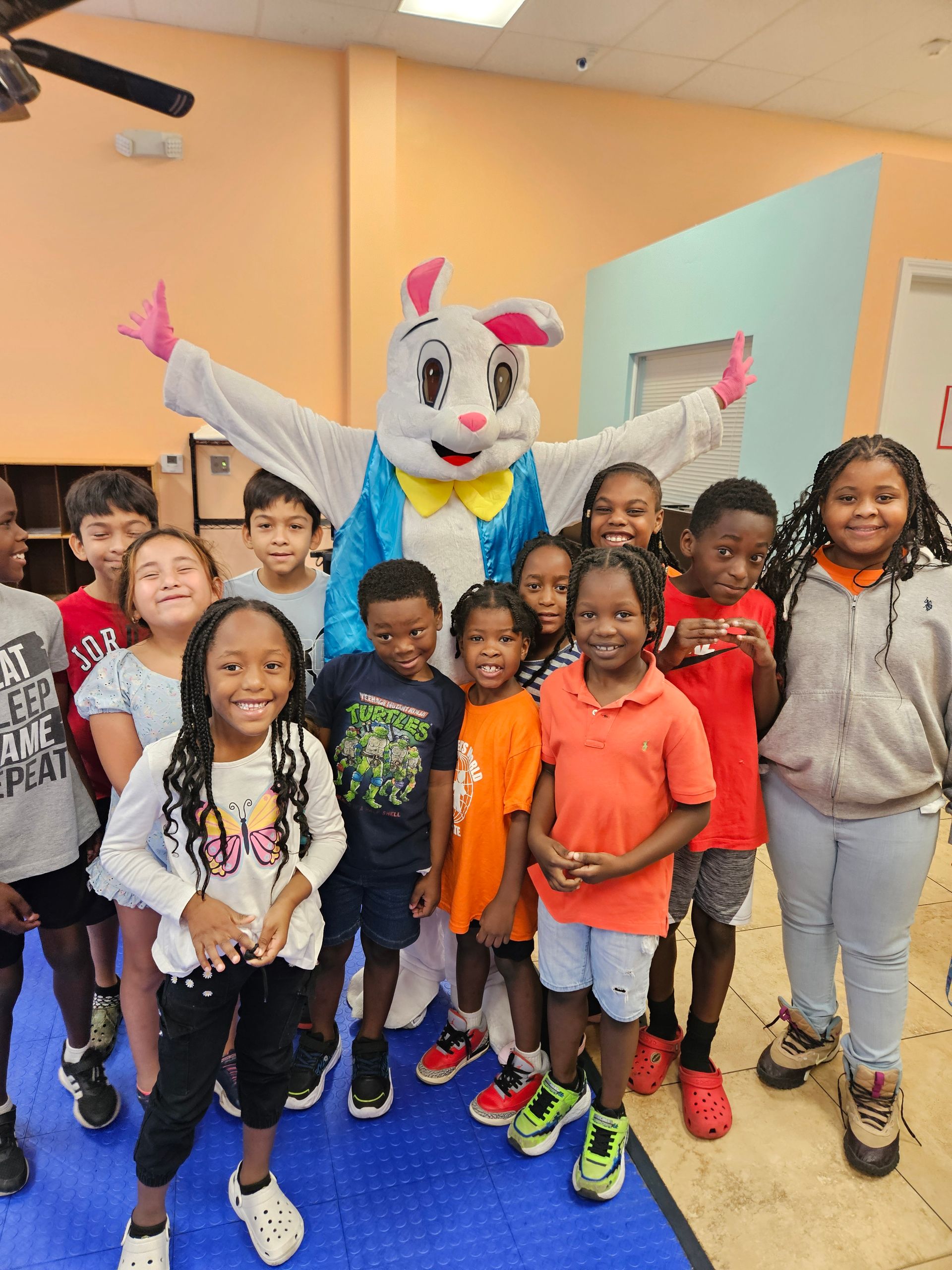 Children pose with the Easter Bunny in a room, many smiling.