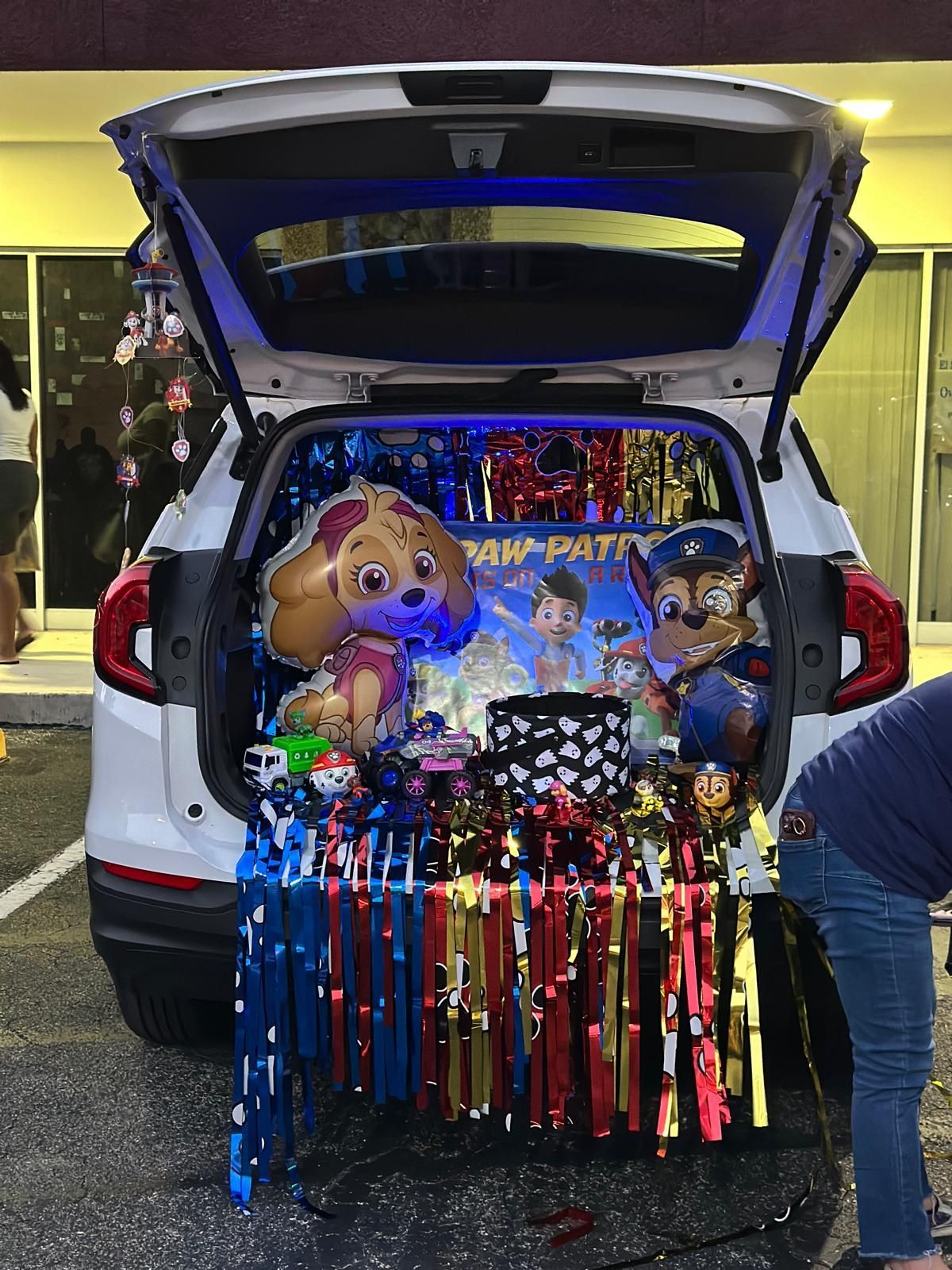Trunk-or-Treat with Paw Patrol theme: Balloons, decorations, and a backdrop in a car trunk.