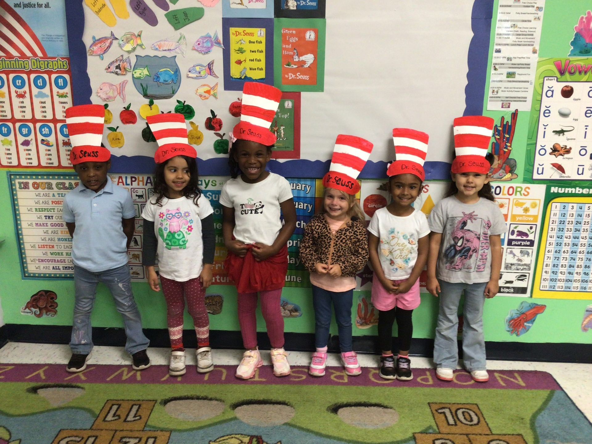 Children in Cat in the Hat hats pose in a classroom.