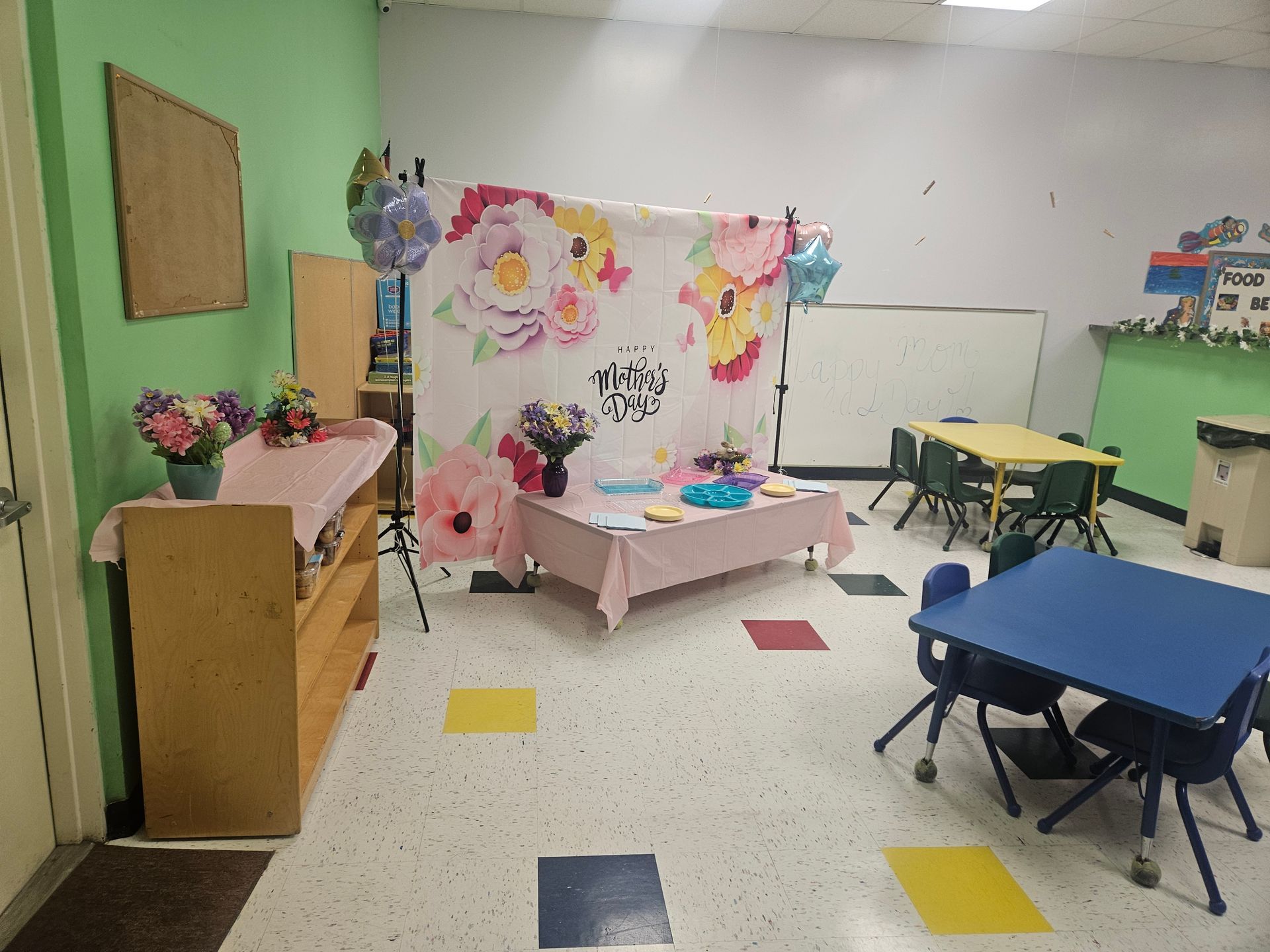 Childcare room with floral backdrop, decorated tables, chairs, and flowers.