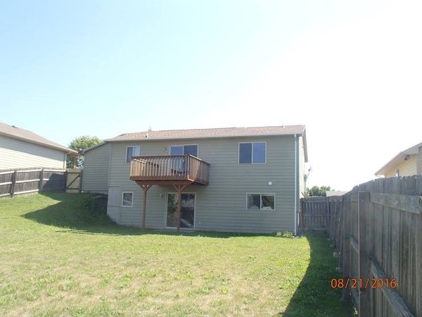 The back of a house with a deck and a fence.