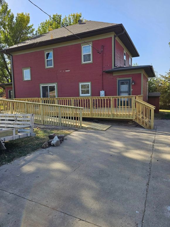 A red house with a wooden deck in front of it.