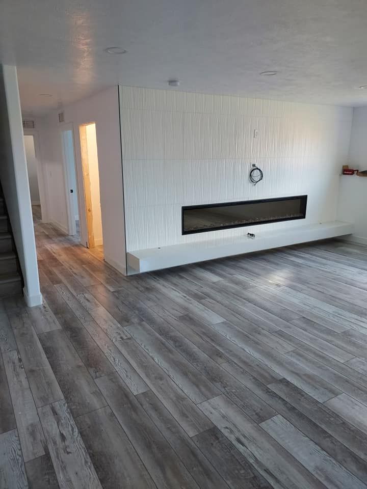 Gray wood-look flooring in a room with a white-paneled wall, fireplace, and hallway.