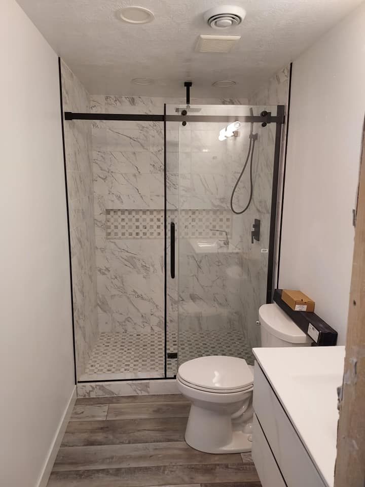 A bathroom with a toilet , sink and shower stall.