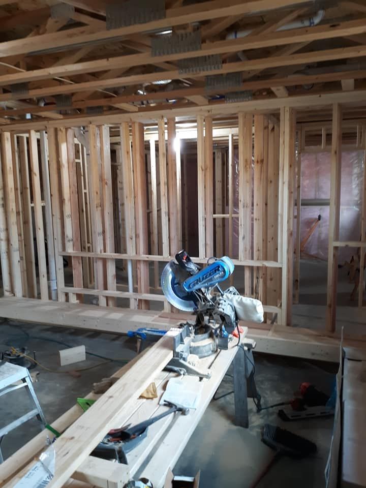Construction site with a miter saw on a stand and wooden framing for walls.