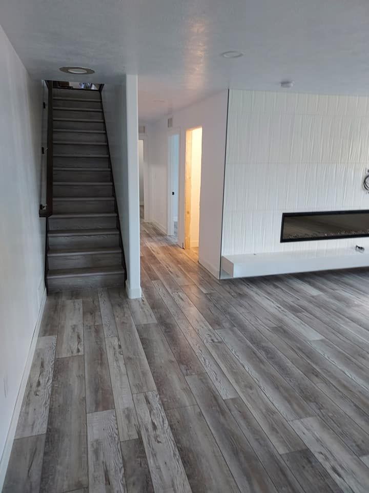 Wooden staircase leads up, hallway extends, white fireplace with black insert.
