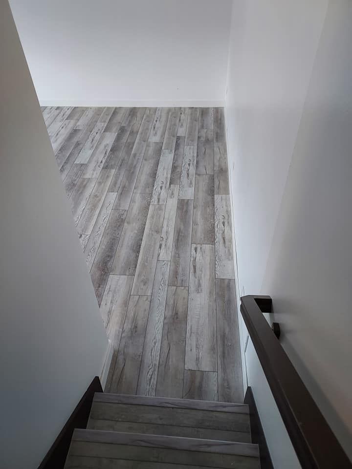 Staircase leading down to a room with wood-look flooring and white walls.