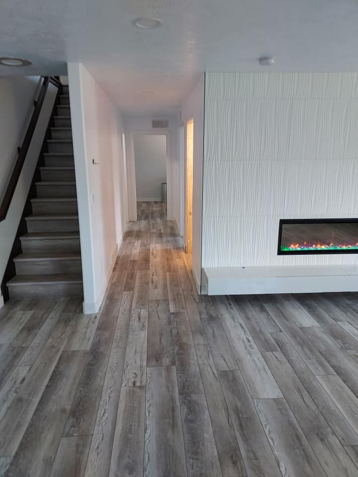 A living room with hardwood floors , stairs , and a fireplace.