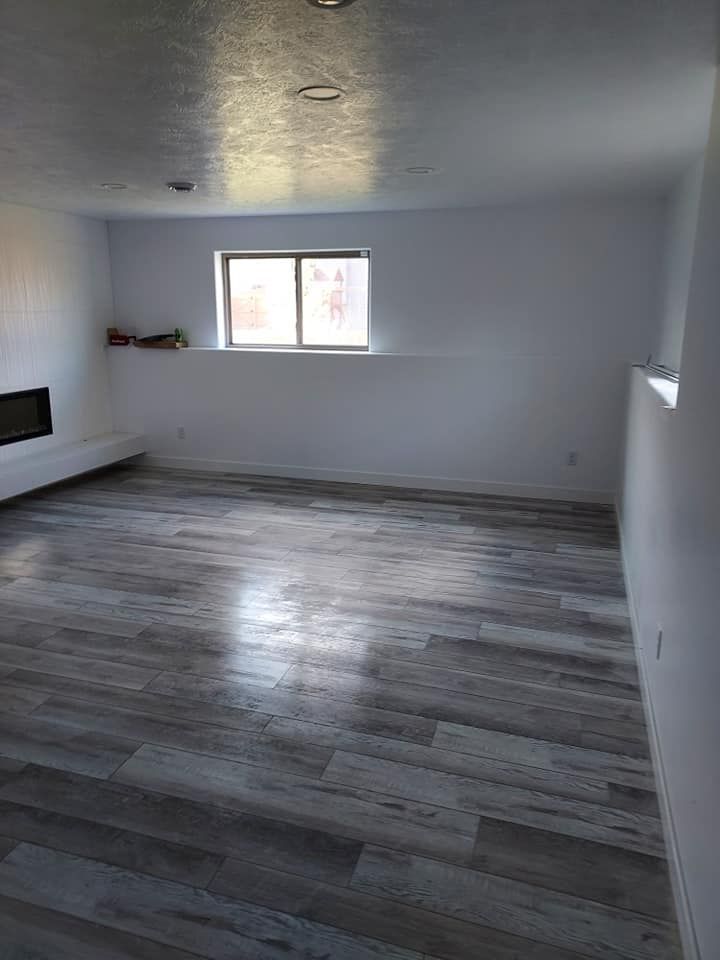 An empty living room with a fireplace and a window.