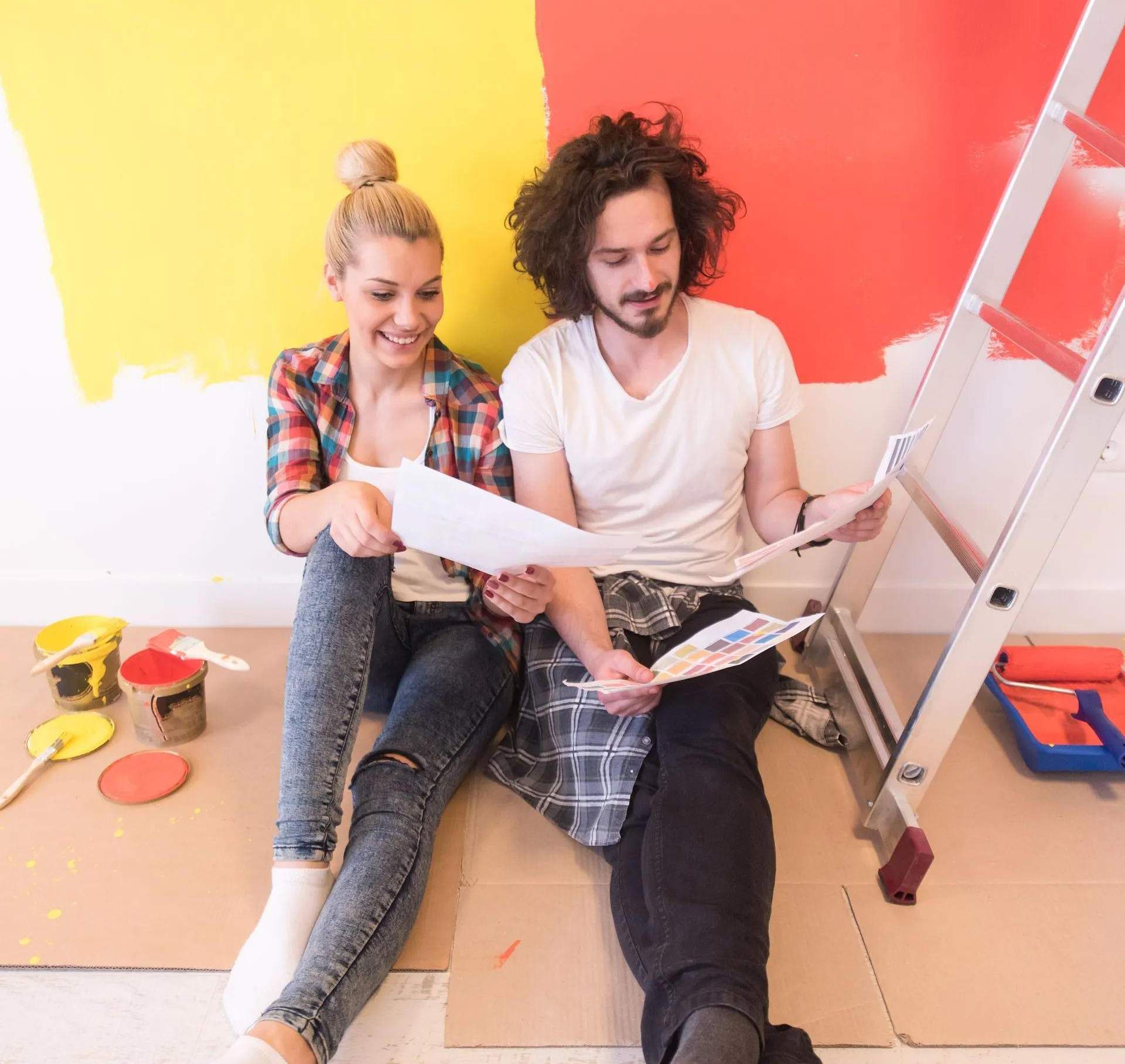 A man and a woman are sitting on the floor looking at a book.