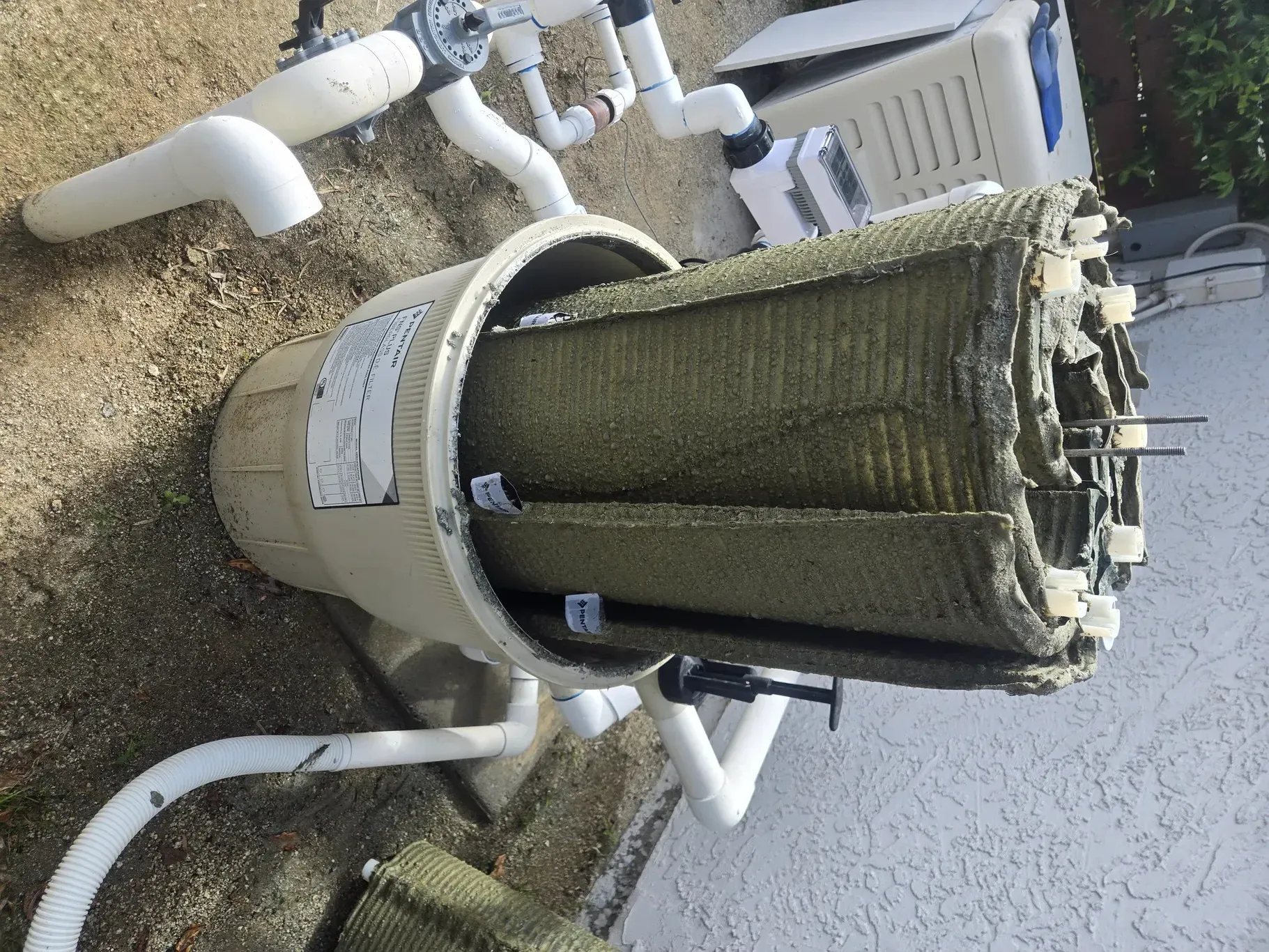 A pool filter cartridge removed from its housing, covered in dirt and debris.