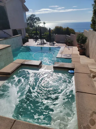 Pool with spa, ocean view. Turquoise water, sunny day, stone deck.
