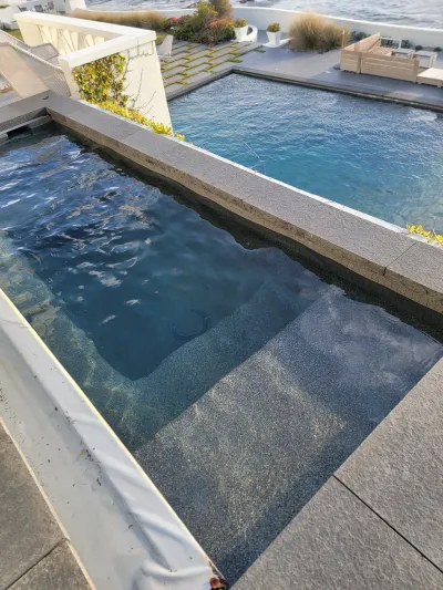 Pool with steps and a view of a larger pool and ocean.