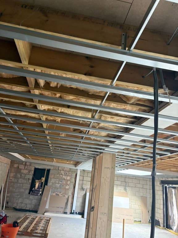 Construction site with exposed ceiling framing, insulation, and unfinished walls.