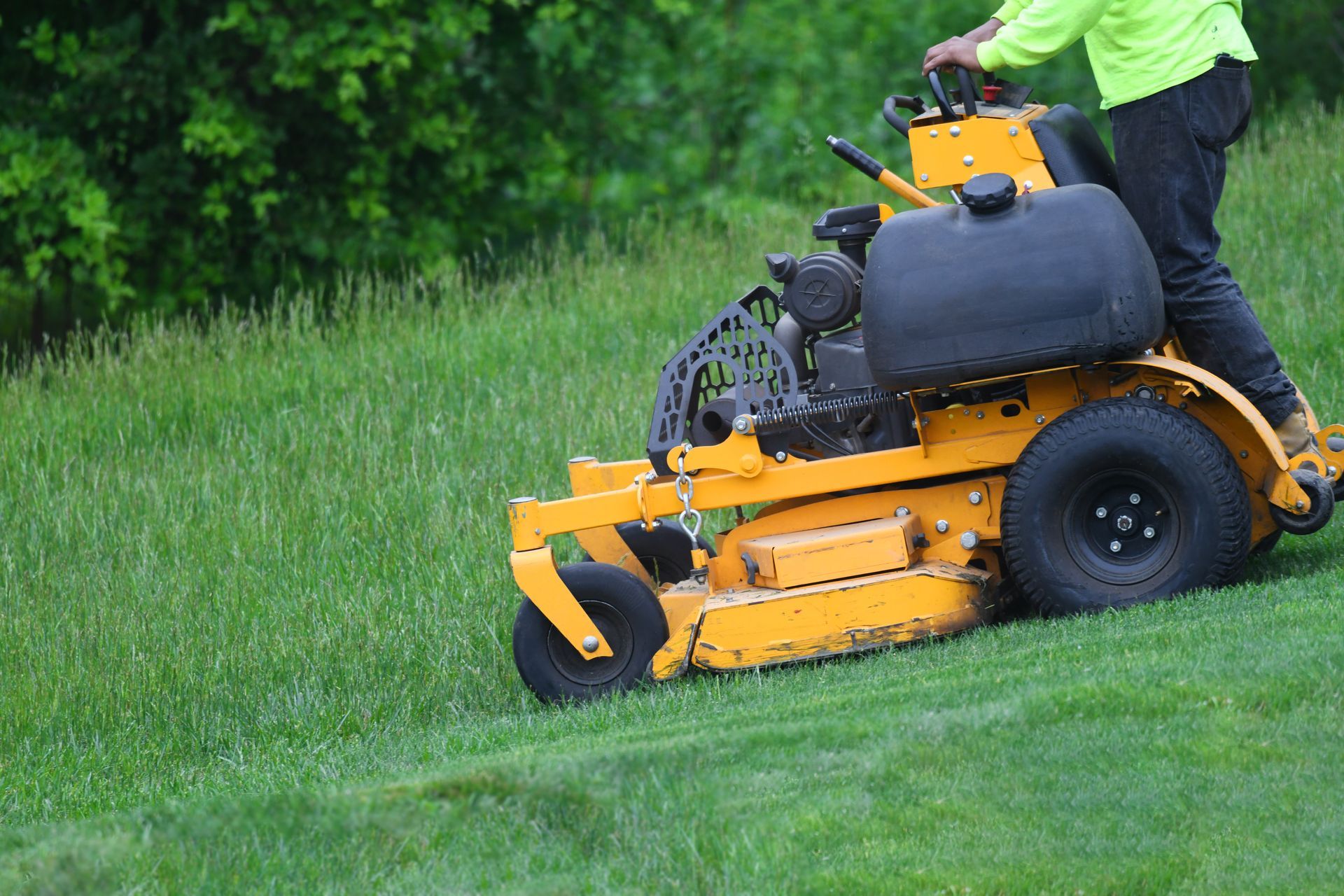 A worker mows the lawn with a lawnmower. A worker mows the lawn with a lawnmower.