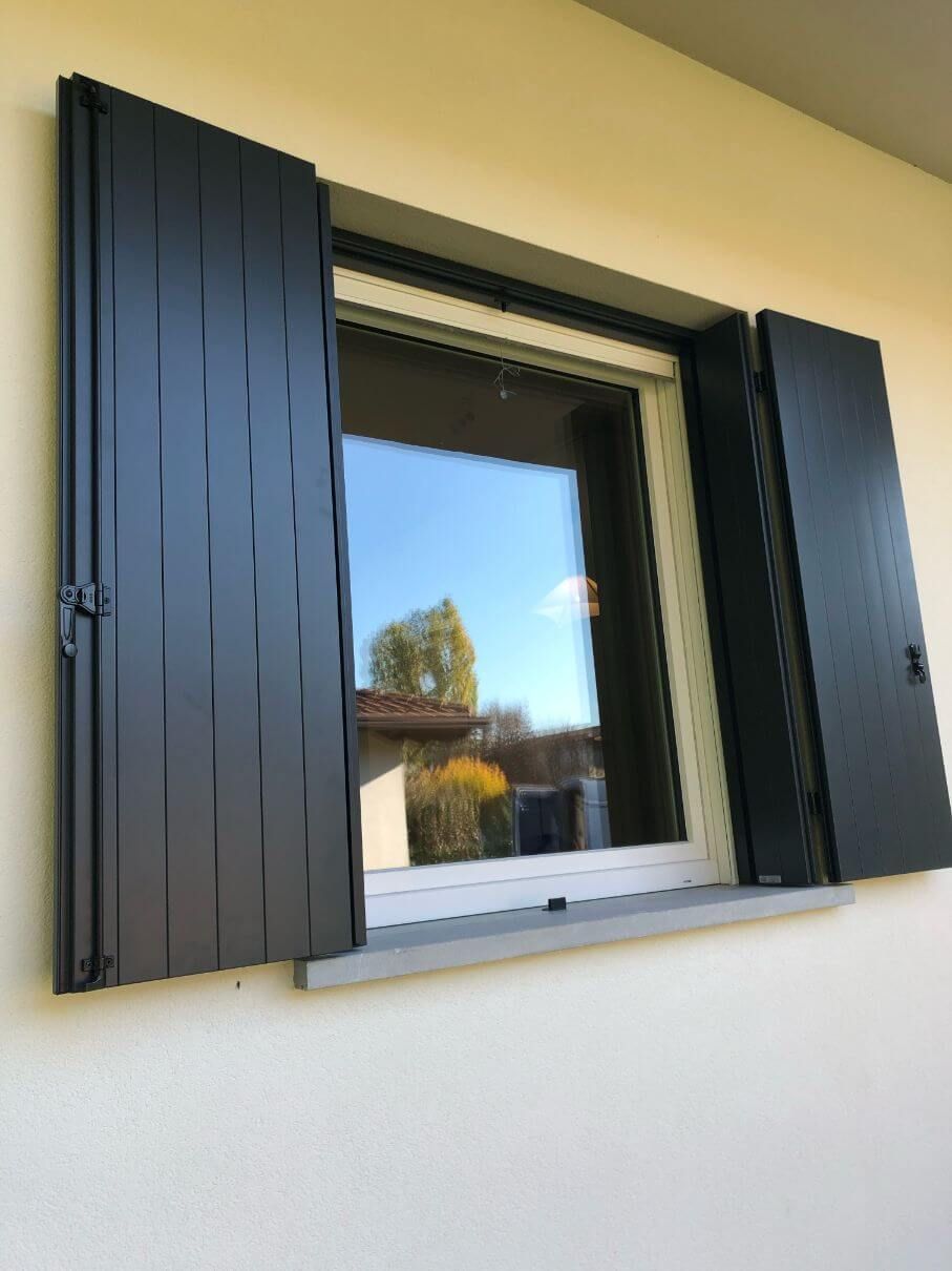 Una finestra con persiane nere su un muro bianco.