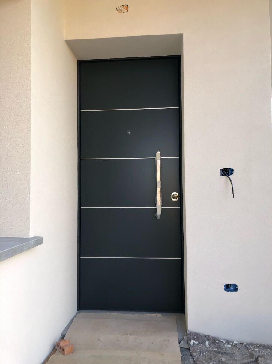 Una porta nera con una maniglia argentata su un muro bianco