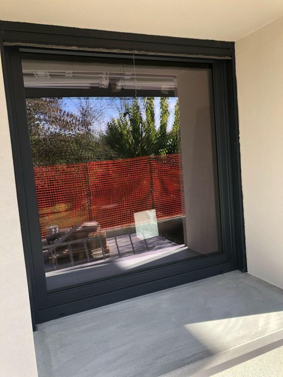 Una grande finestra con il riflesso di una recinzione.