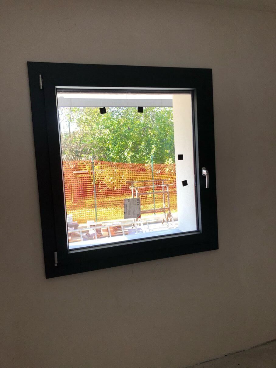 Una finestra quadrata con una cornice nera è appesa a una parete.