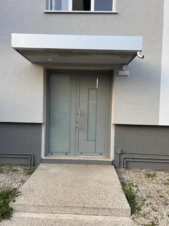 Una porta bianca con una tettoia sopra si trova sul lato di un edificio.