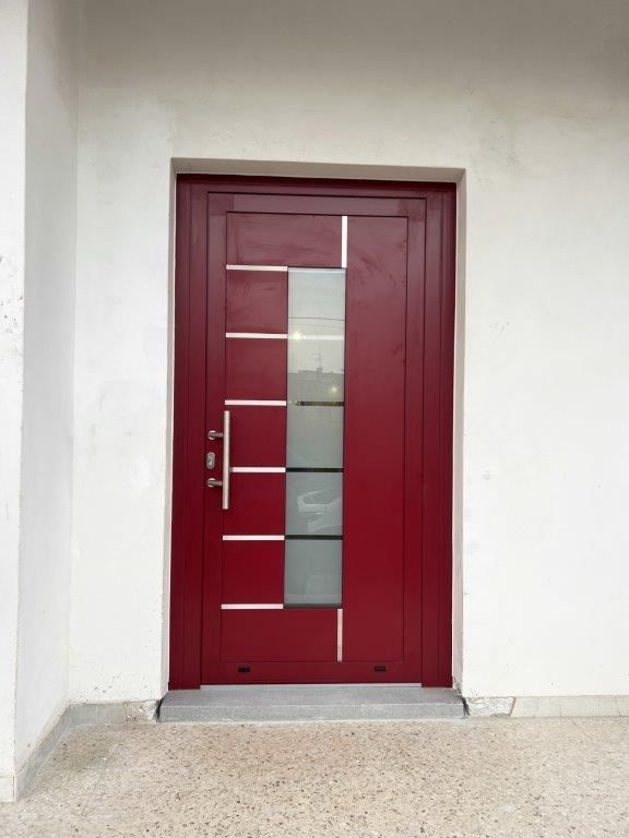 Una porta rossa con una maniglia in acciaio inossidabile è su un muro bianco