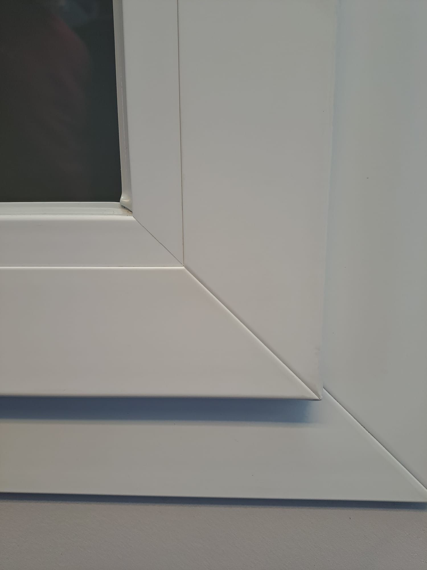 Un primo piano della cornice bianca di una finestra su una parete bianca.