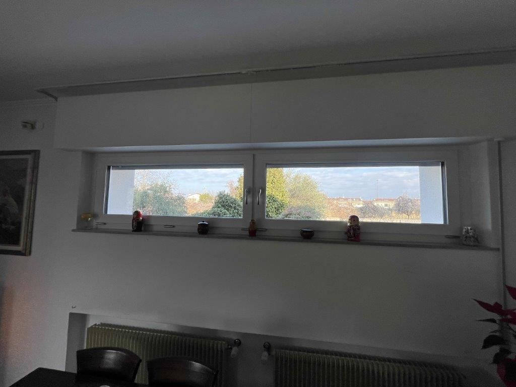 Un soggiorno con una grande finestra e un termosifone.