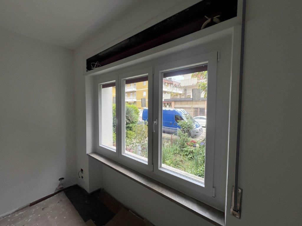 Una stanza con tre finestre e un furgone blu sullo sfondo.